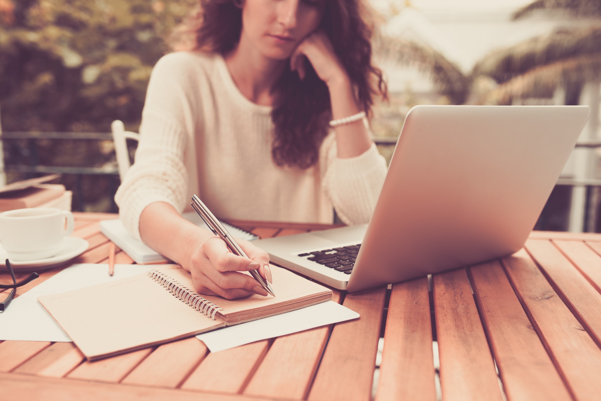 Woman working on computer and writing down her thoughts